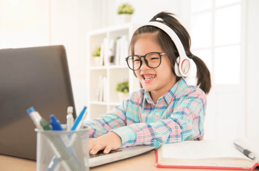 little girl with glasses and headphones using a computer