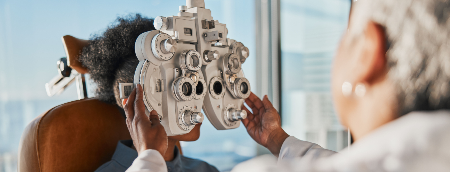 Eye Exam An optometrist conducts an eye exam using a phoropter on a seated patient in a clinic.