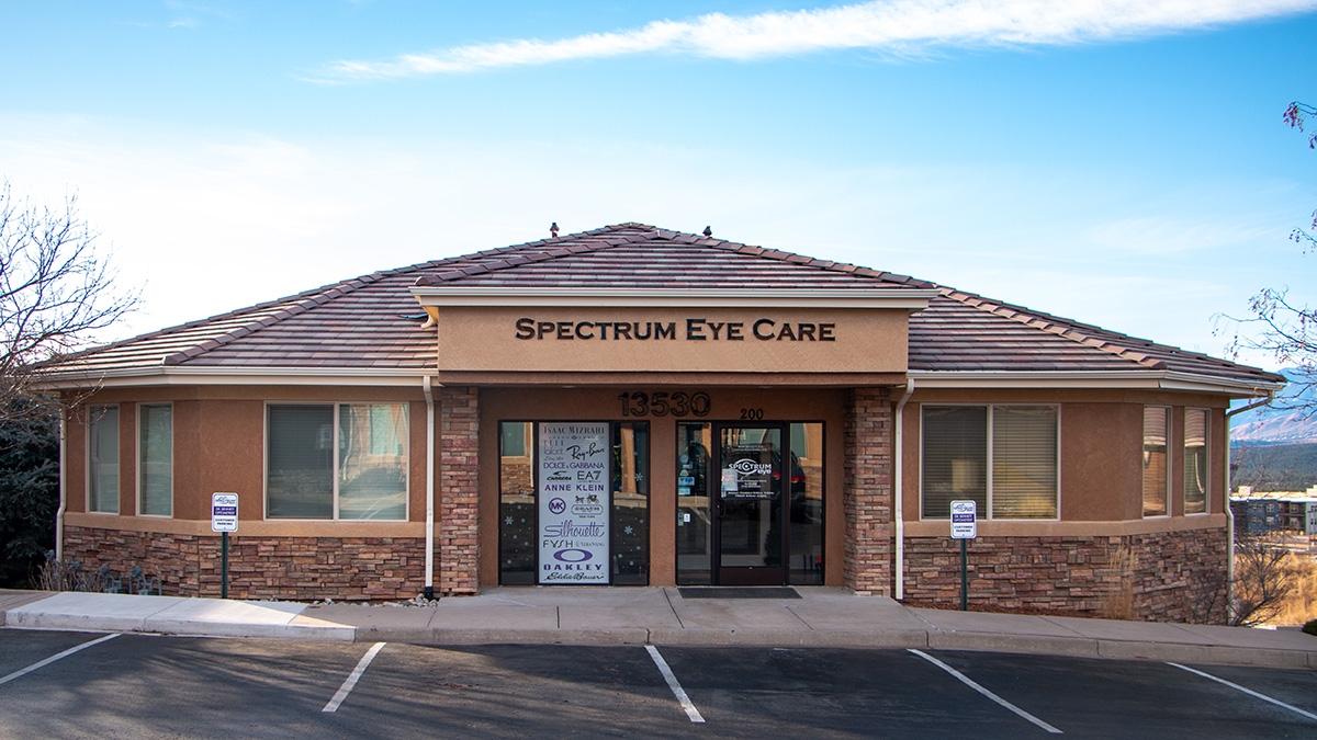 Single-story building with sign reading "Spectrum Eye Care" above the entrance, two large windows, a glass door, and empty parking spaces in front.