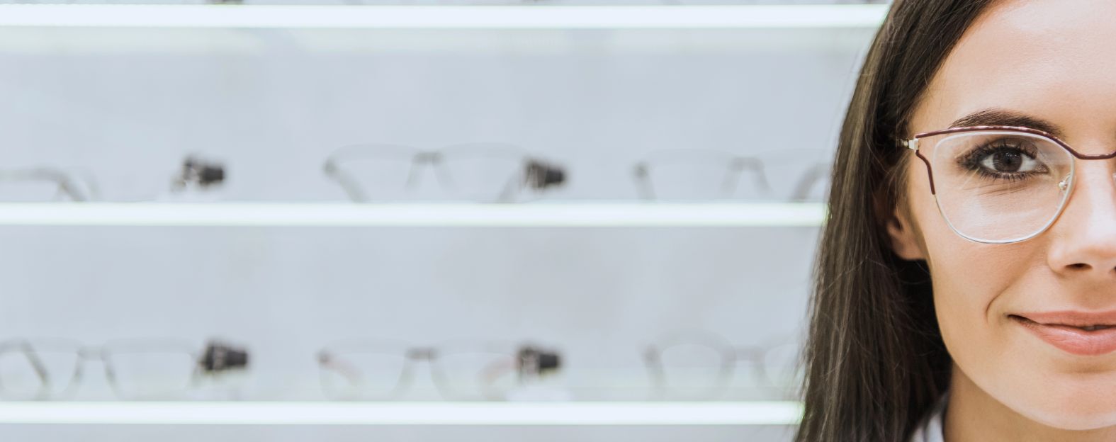 A woman with glasses is shown in close-up on the right side, with rows of eyeglass frames displayed on shelves in the background.